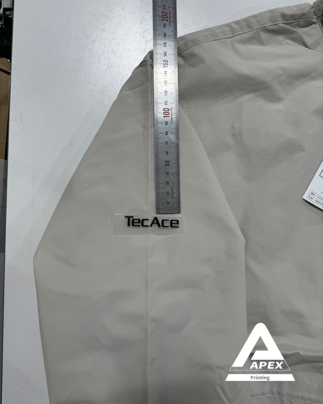 'TecAce' 로고의 위치를 조정하는 과정, 자로 길이를 측정하며 배치 확인 중.