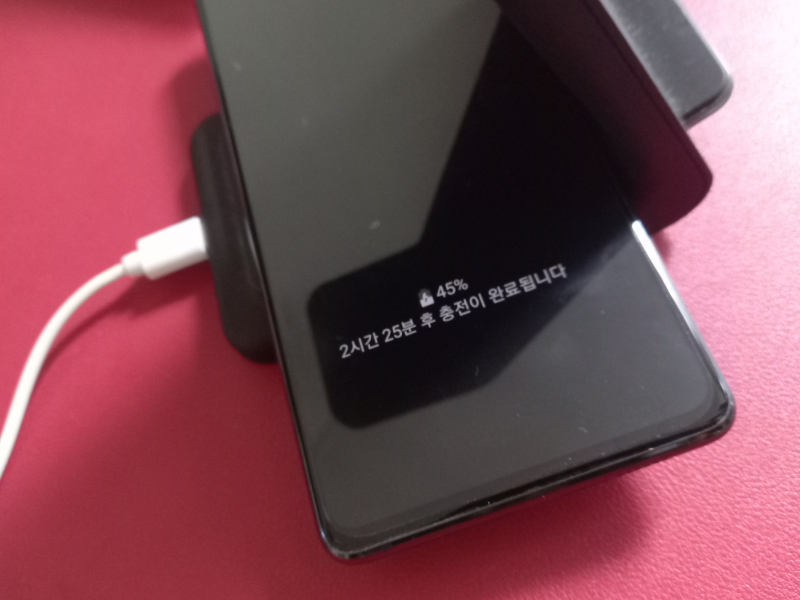 갤럭시 휴대폰에 뜬 충전기 USB 포트 물기감지 메시지로 무선 충전기를 사용하는 모습