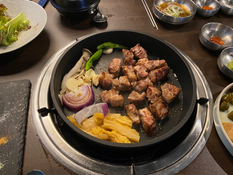 프라이팬에 두툼한 고기와 야채가 맛있게 구어지고 있다