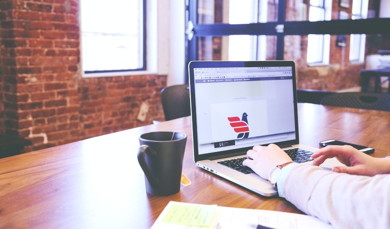 A person working on a laptop in a modern workspace with a U.S.-related logo on screen, symbolizing F-1 visa preparation and DS-160 completion.