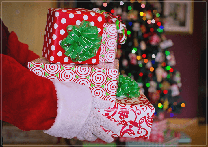 산타복장의-팔이-흰색과-초록색-빨간색으로-포장된-선물-상자를-여러개-쌓아-들고있다