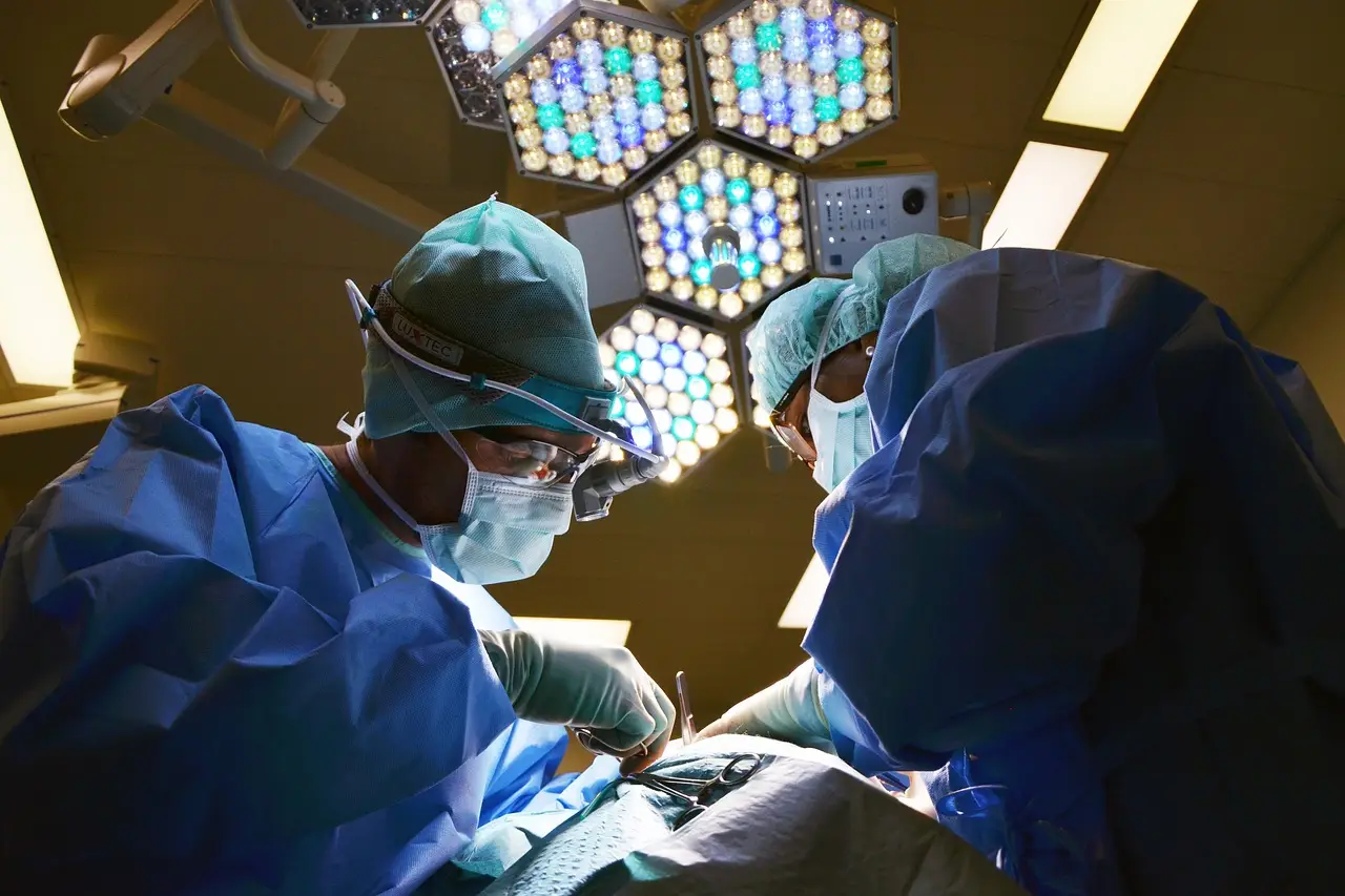 응급실-수술실 노라천정에 있는 백열등 아래서 파란 수술복을 입고 수술하고 있는 의사 2명