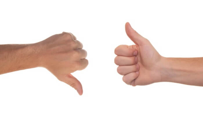 엄지 손가락이 하나는 밑으로, 하나는 위로 향하고 있는 모습. 비교를 나타내고 있다.