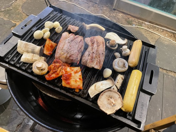 불판 위에 올린 삼겹살과 소시지, 버섯 모임