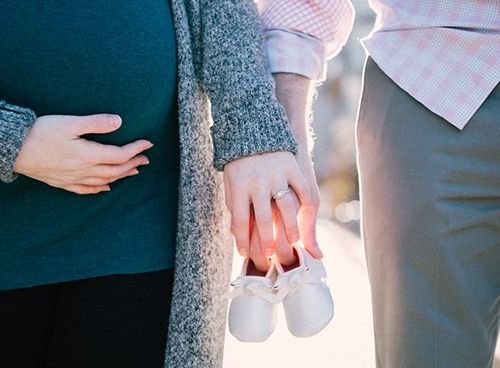 임신한 엄마와 아빠가 아기 신발을 손에 같이 잡고 있는 사진