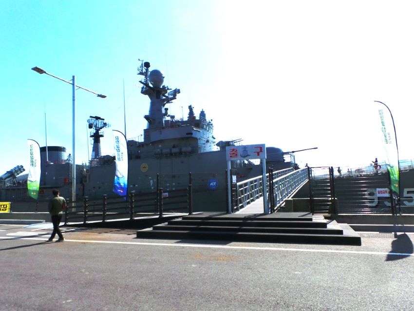두 장의 사진은 외포리 선착장 함상공원에 고박된 군함 955호, 푸른 하늘, 군함에 오르 내리는 관광객들,