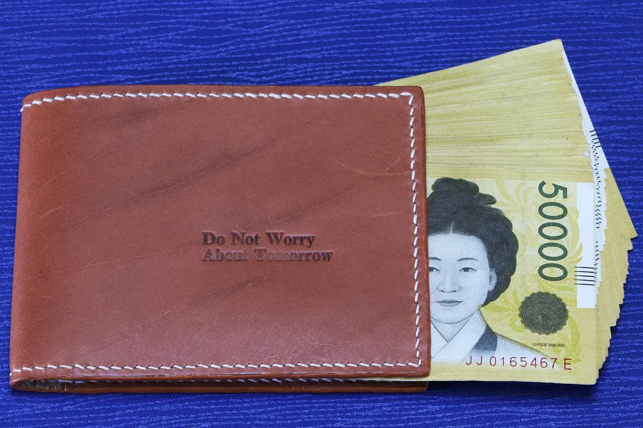 신용불량자- 접힌 갈색 반지갑에 꽂혀있는 5만원권이 놓인 파란 테이블