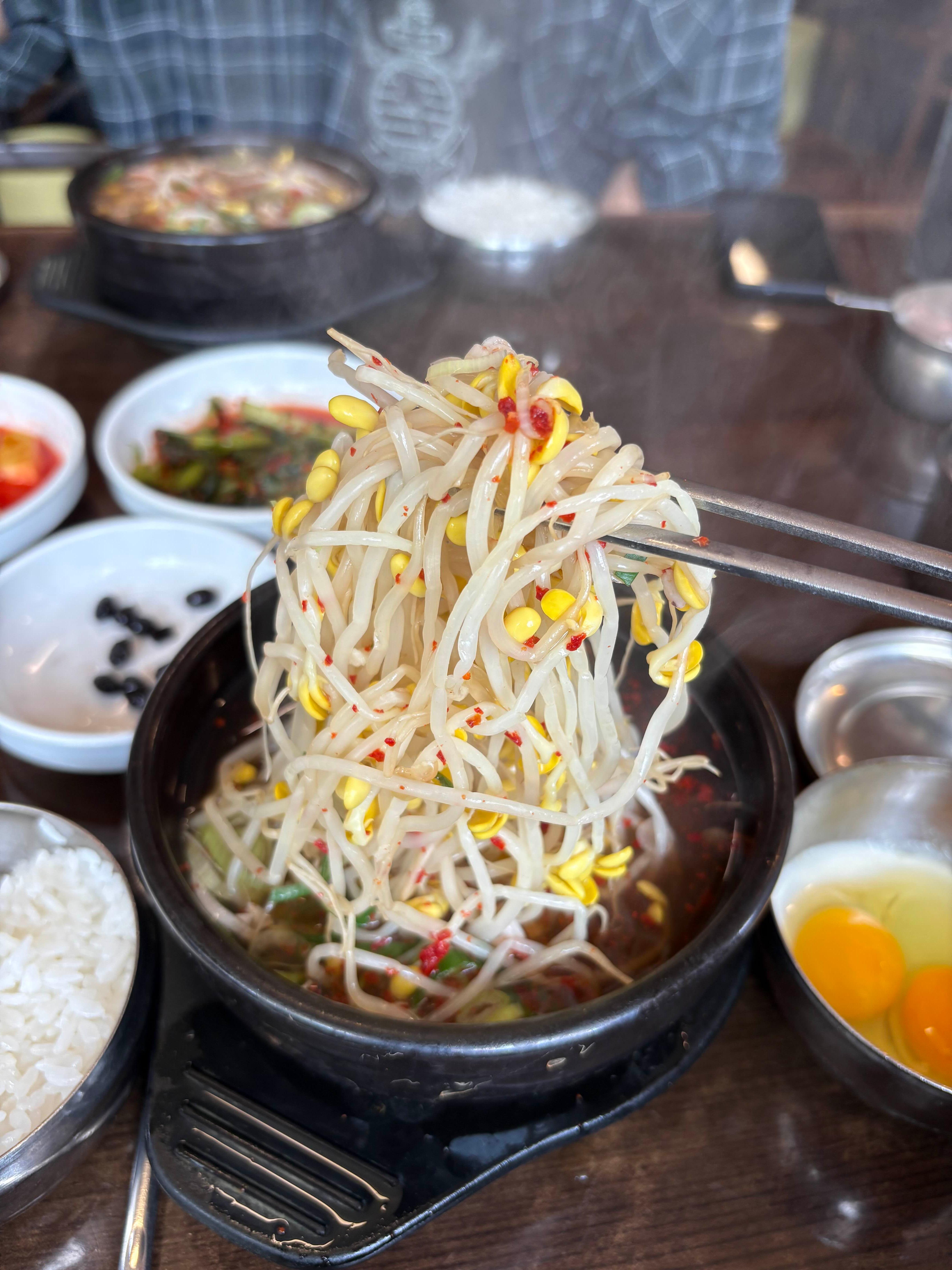 alt=&quot;젓가락으로 콩나물을 집어든 모습. 국물은 보이지 않지만 콩나물이 수북히 들어있는 것이 특징이다.&quot;