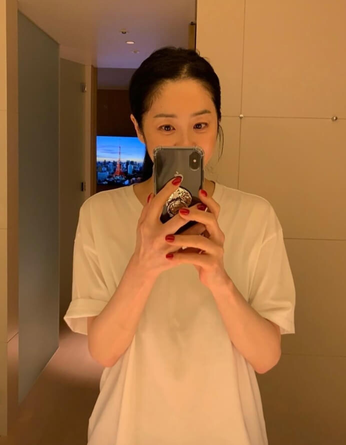 두손으로-핸드폰을들고있는-머리묶은여성의모습