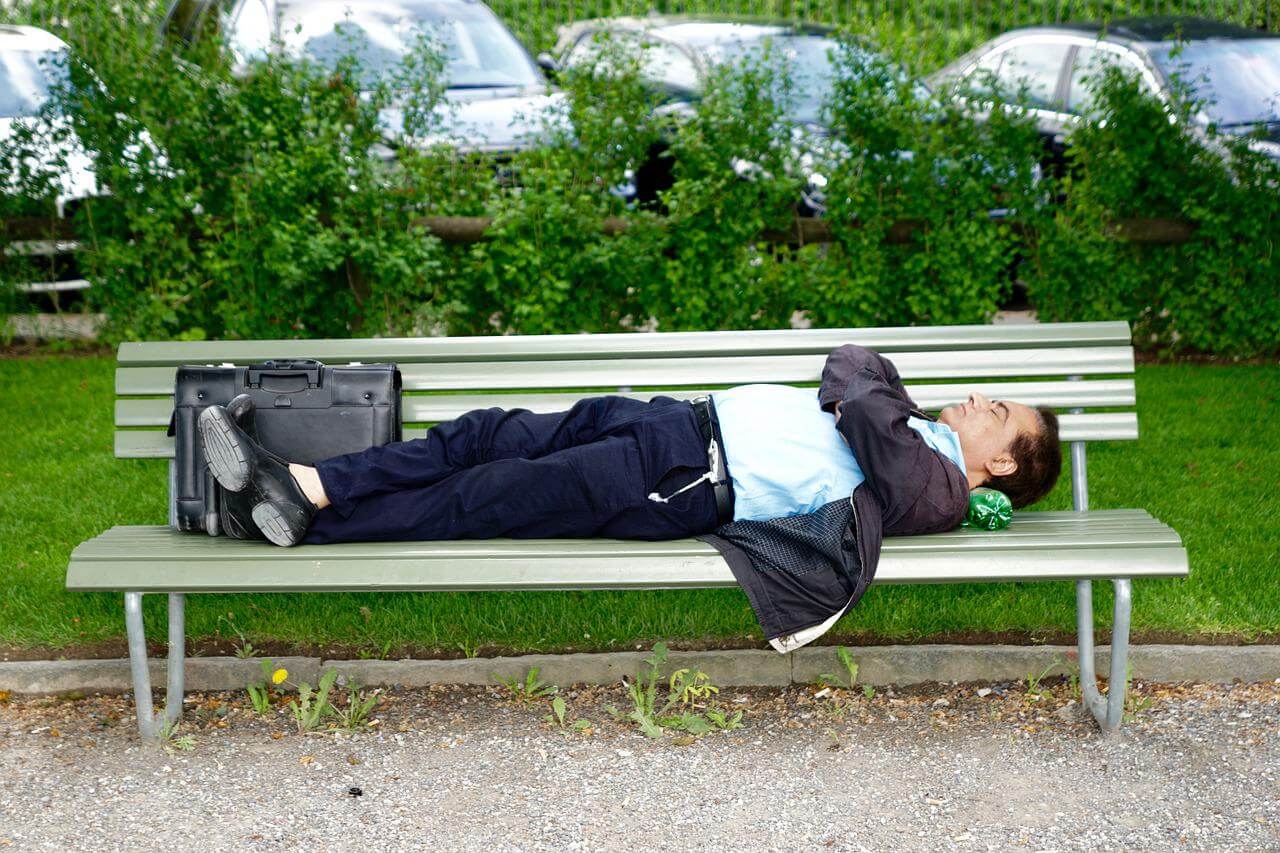 길거리 벤치에 누워서 잠을 자고 있는 남성