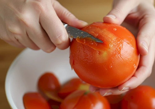 데친 잘 익은 토마토의 껍질을 손으로 부드럽게 벗기는 모습 사진
