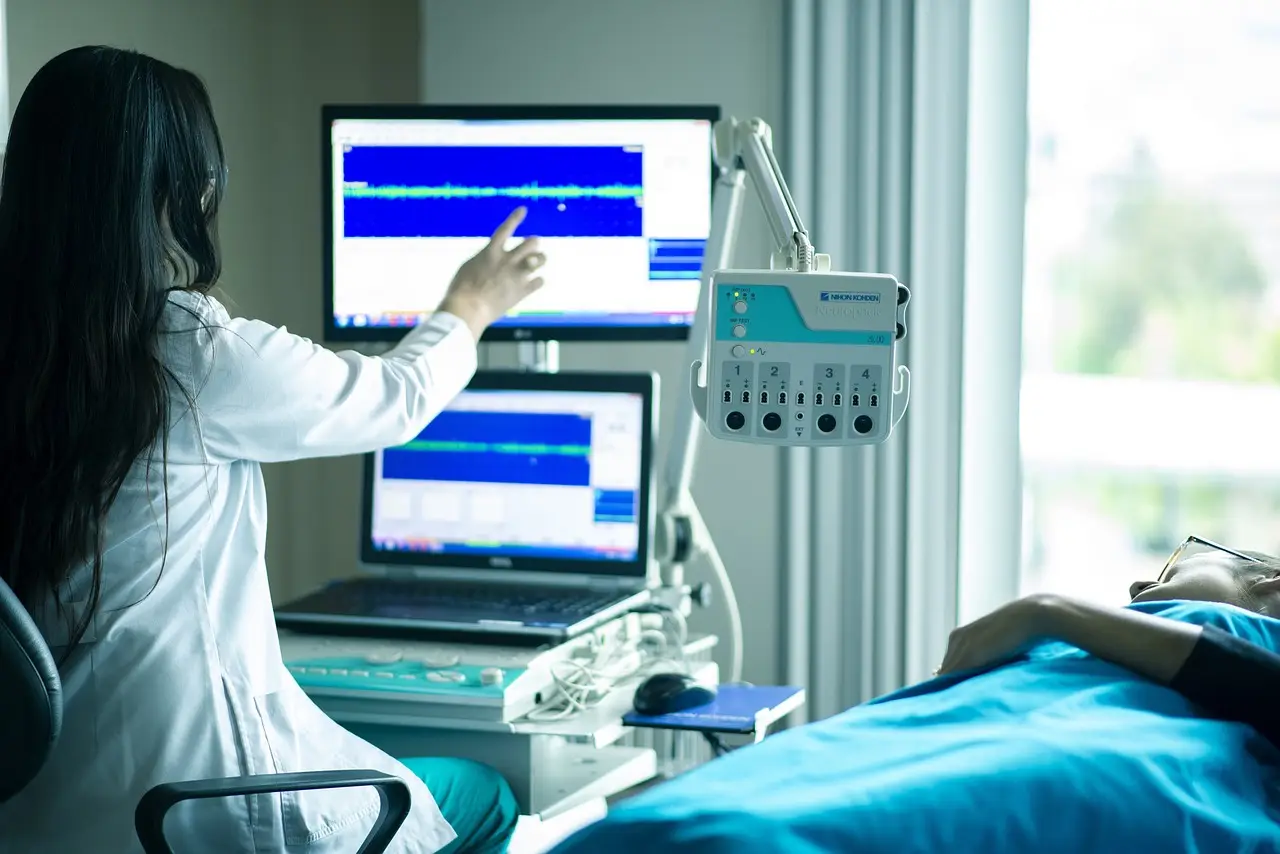 건강-컴퓨터 모니터를 통해 설명하는 흰가운의 의사와 우측 침대에 누워 설명을 등고있는 환자