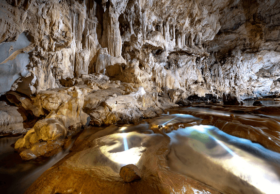 동굴내부에-물이흐르고-동굴위에는-종류석들이-있는-사진