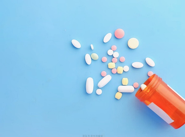 주황색 약병에서 쏟아진 다양한 색깔의 약들