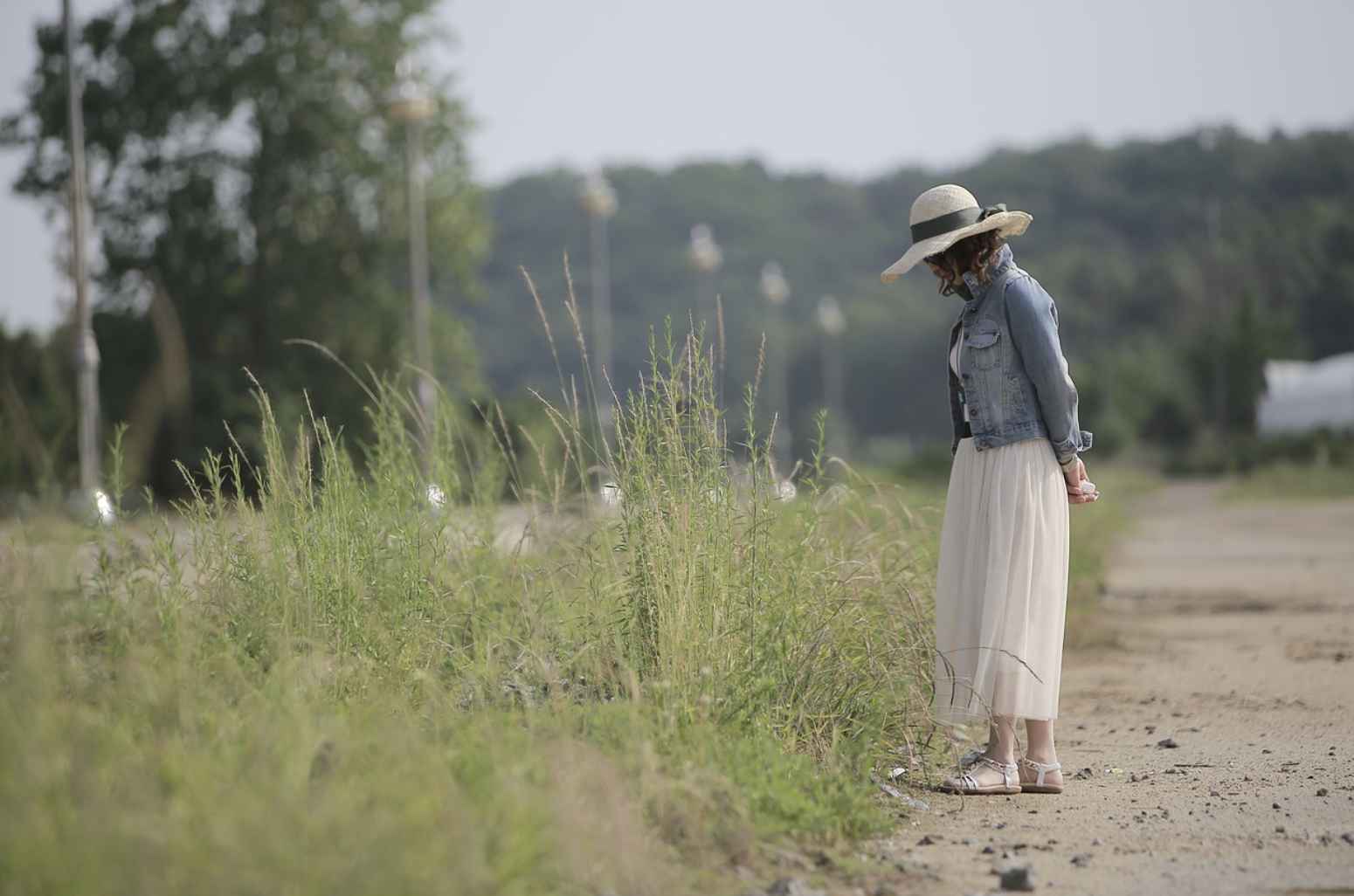 풀밭에서 산책하는 모자 쓴 여성
