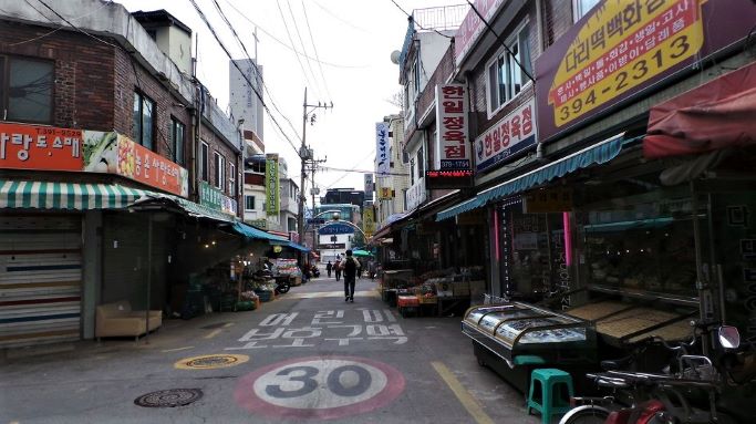 간판들이 즐비한 시장골목 풍경&#44; 바닥에는 어린이 보호구역&#44; 흰글씨&#44; 시장통 걸어가는 사람들&#44;