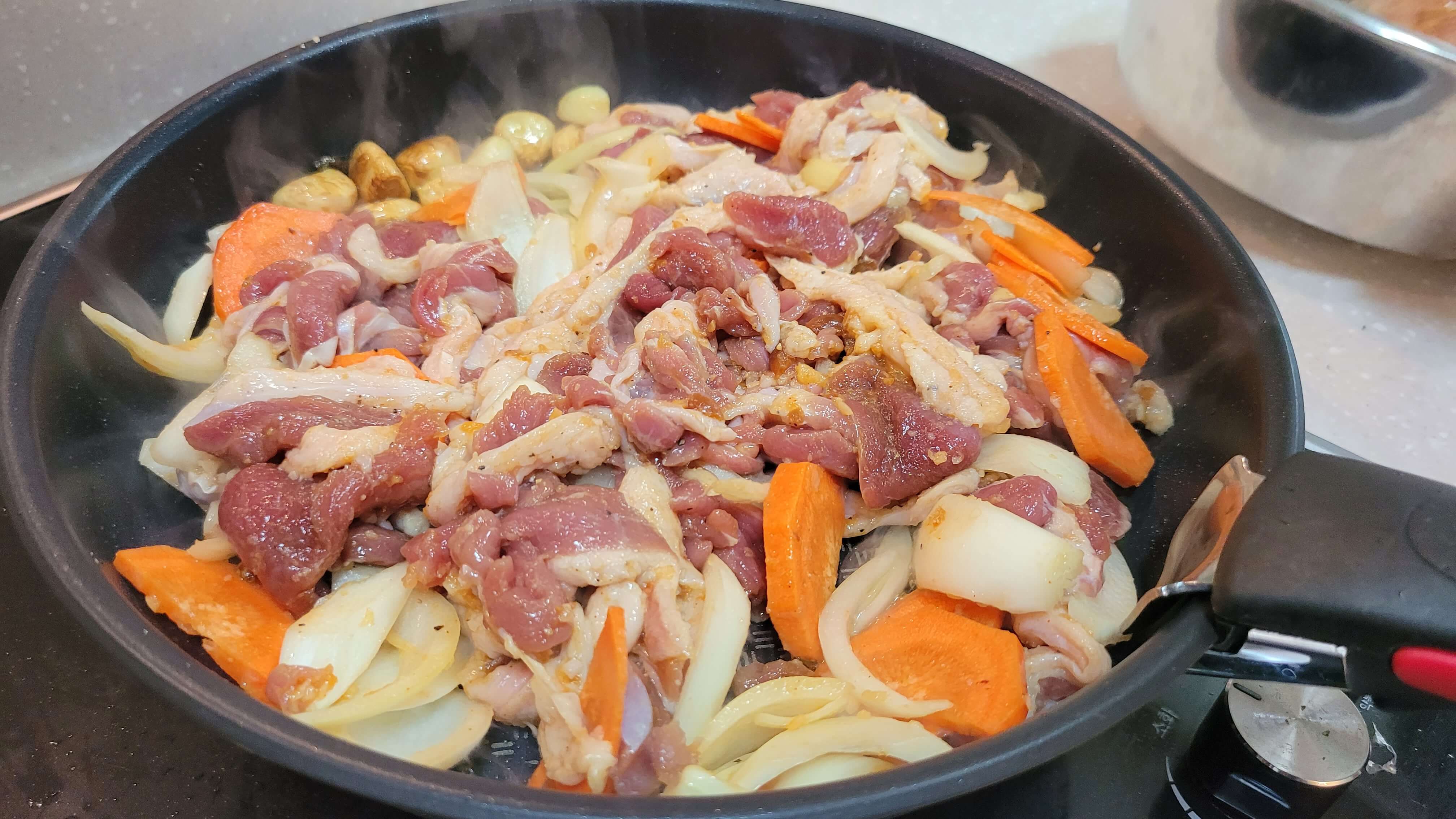 &quot;Seasoned duck meat being grilled on a high flame in a skillet.&quot;