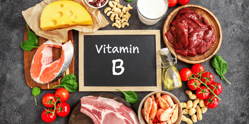 까만보드에 Vitamin B가 흰색 분필로 적혀있고&#44; 주위에 치즈&#44; 연어&#44; 육류&#44; 방울토마토&#44; 땅콩 등이 놓여져 있다