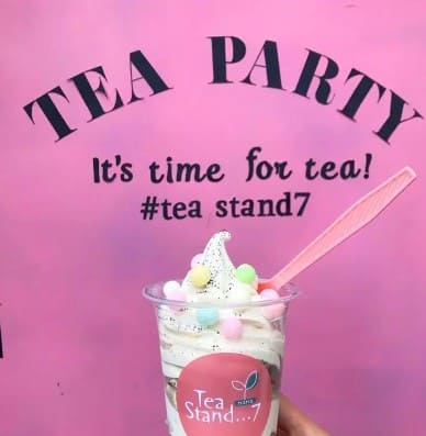 핑스색 벽지에 &#39;tea party&#39;라고 적혀있고 그 앞에 아이스크림을 들고 있다.