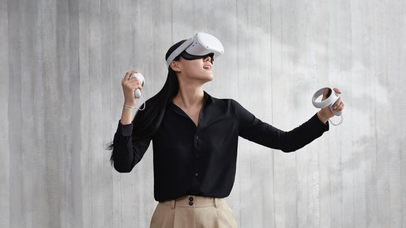 한 여성이 양 손에 VR체험을 할 수 있는 도구를 잡고 있고 눈에는 VR체험용 렌즈를 끼고 가상현실을 즐기고 있다