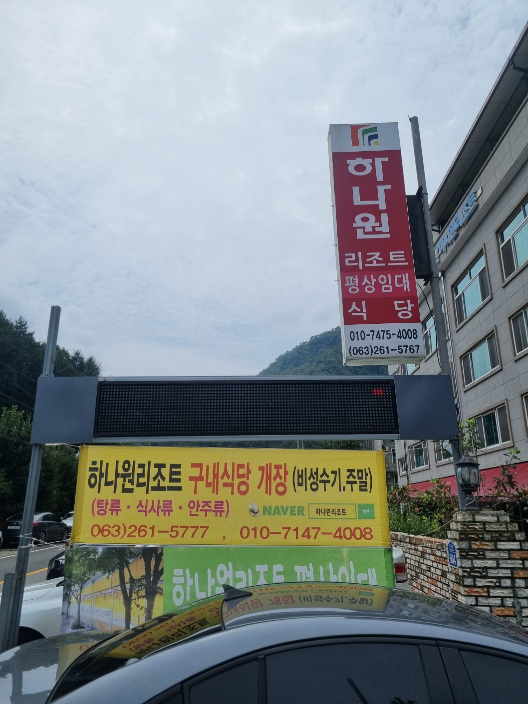 가까이에서 보이는 하나원 리조트 간판. 빨간색 배경에 흰색 글씨로 하나원 리조트 평상임대 식당 이라고 쓰여있다.