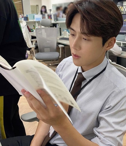 배우 김선호씨가 직장 복장을 하고 책을 읽고있는 반 측면 사진