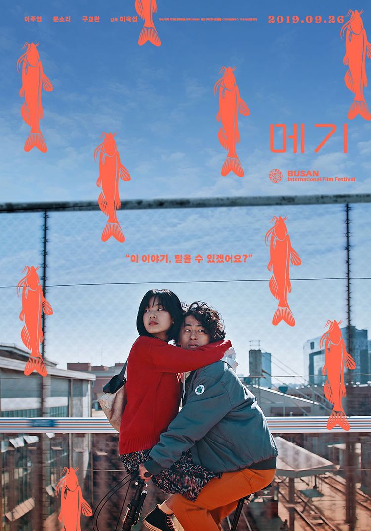 메기 영화 포스터&#44; 이주영과 구교환이 자전거를 같이 타고 지나가고 있다. 메기 모양의 그림이 포스터에 그려져 있다.