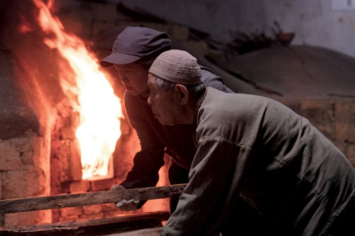 알트태그-영화 불숨의 한 장면입니다. 아버지와 딸 부녀 도공이 함께 가마에 불을 넣고 있습니다.