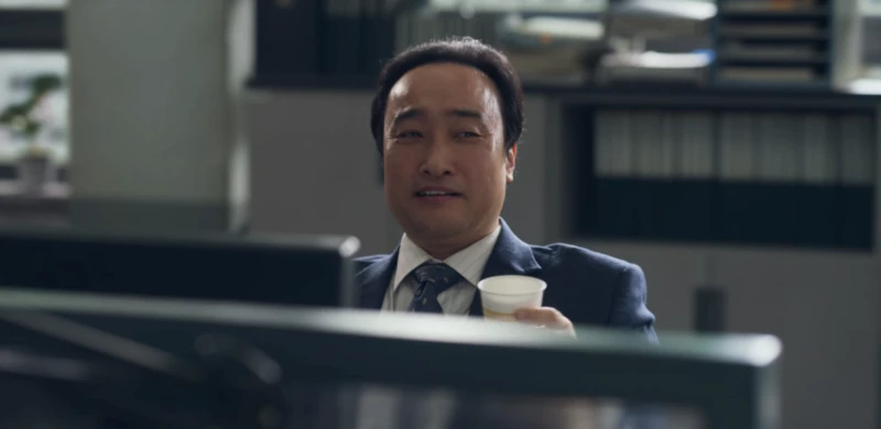 사무실 책상에 앉아 커피가 든 종이컵을 들고 있는 드라마 마스크걸의 부장 캐릭터