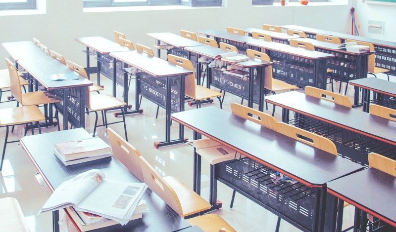 An empty university classroom with open books and sunlight, symbolizing the completion of academic life and the transition to professional planning.
