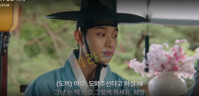 갓을 쓰고 하늘색 두루마기를 입은 도겸. 자막은 &amp;quot;(도끼) 아유&amp;#44; 도와주신다고 하실 때 그냥 눈 딱 감고 그렇게 하세유&amp;#44; 제발&amp;quot;
