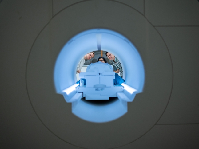 텍사스대의 알렉스 후스 (왼쪽) 교수와 박사과정의 세일리 제인(가운데)&#44; 제리 탕(오른쪽) 연구원이 MRI 장치 앞에서 실험을 준비하고 있다. 연구진은 인공지능에게 뇌 영상을 학습시켜 사람의 생각을 읽는 능력을 개발했다.