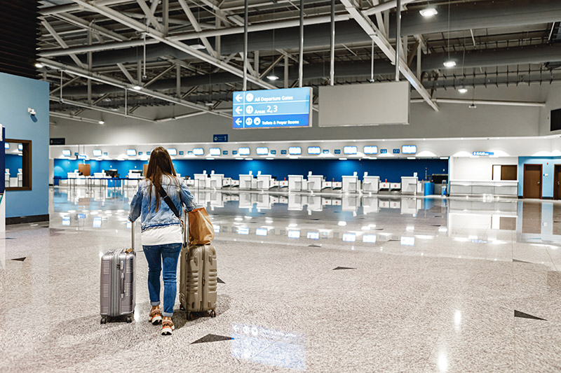 woman-walks-along-airport-with-suitcases