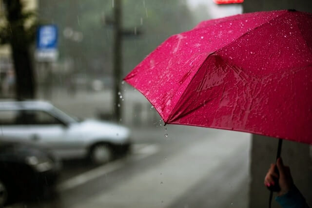 비오는 거리에서 우산을 들고 서있는 모습
