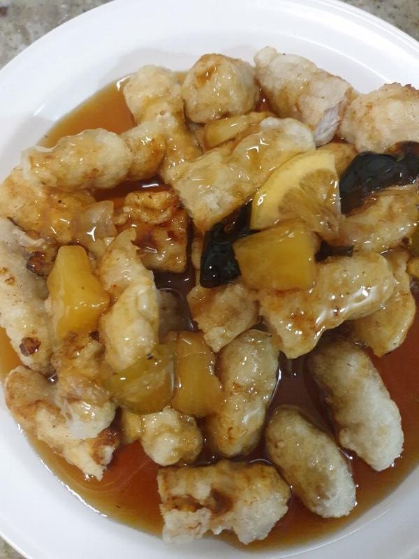 찹쌀탕수육을 다 조리해서 접시에 다은 사진. 피는 하얀 찹쌀 피고 소스에는 레몬과 파인애플이 들어 있다. 매우 맛있어 보임.