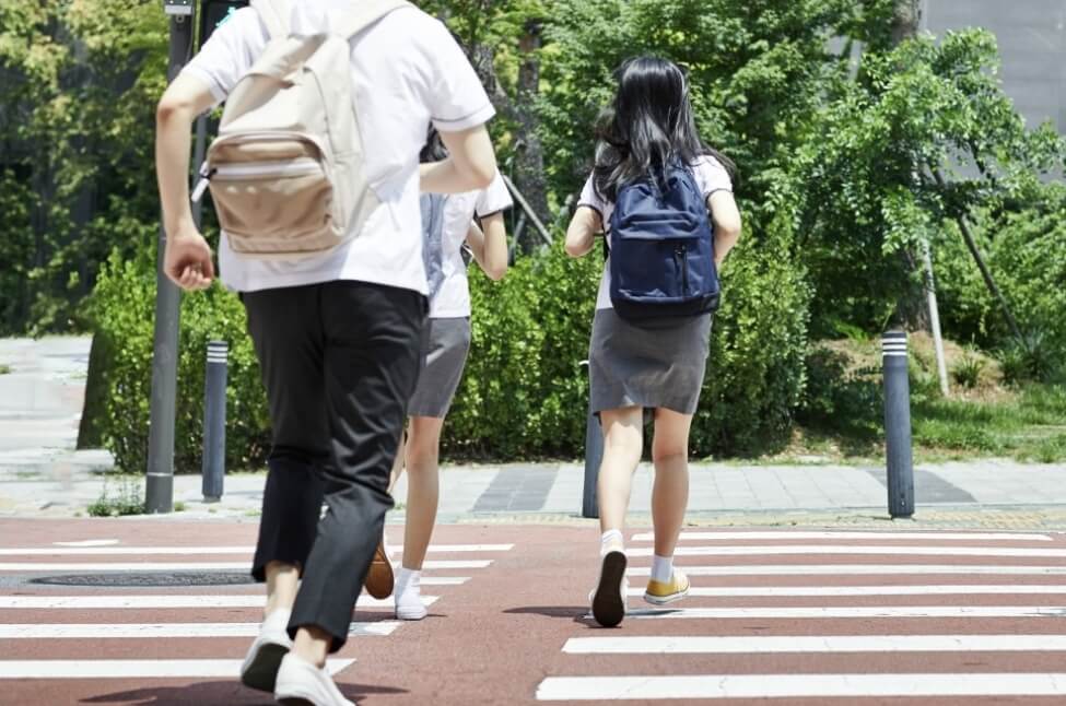 학생들이 학교에 늦어 횡단보도에서 뛰어가고 있다