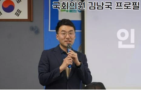 김남국 국회의원이 마이크를 들고 강연하는 모습임. 진남색의 정장을 입고 안경을 쓰고 있음.