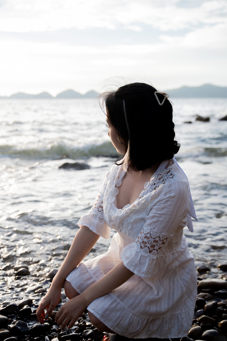 바닷가 앞 쪼그려 앉아있는 여성사진

