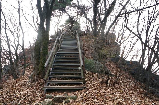 급급경사 봉우리에 급급경사 철계단&#44; 진한 회색 페인트칠&#44; 봉우리는 암봉&#44; 뒤로는 잡목&#44; 하얀 하늘&#44;