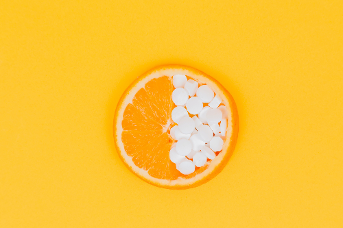 동그란 오렌지 껍질 안에 반은 오렌지과육&#44; 반은 흰색알약이 채워져 있는 사진