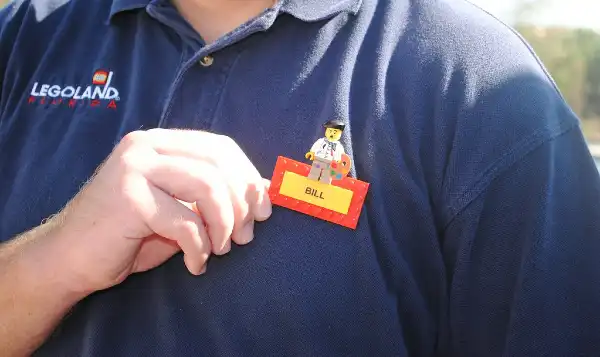 남색 유니폼을 입은 남자가 자신의 이름표를 고쳐 잡고 있다.