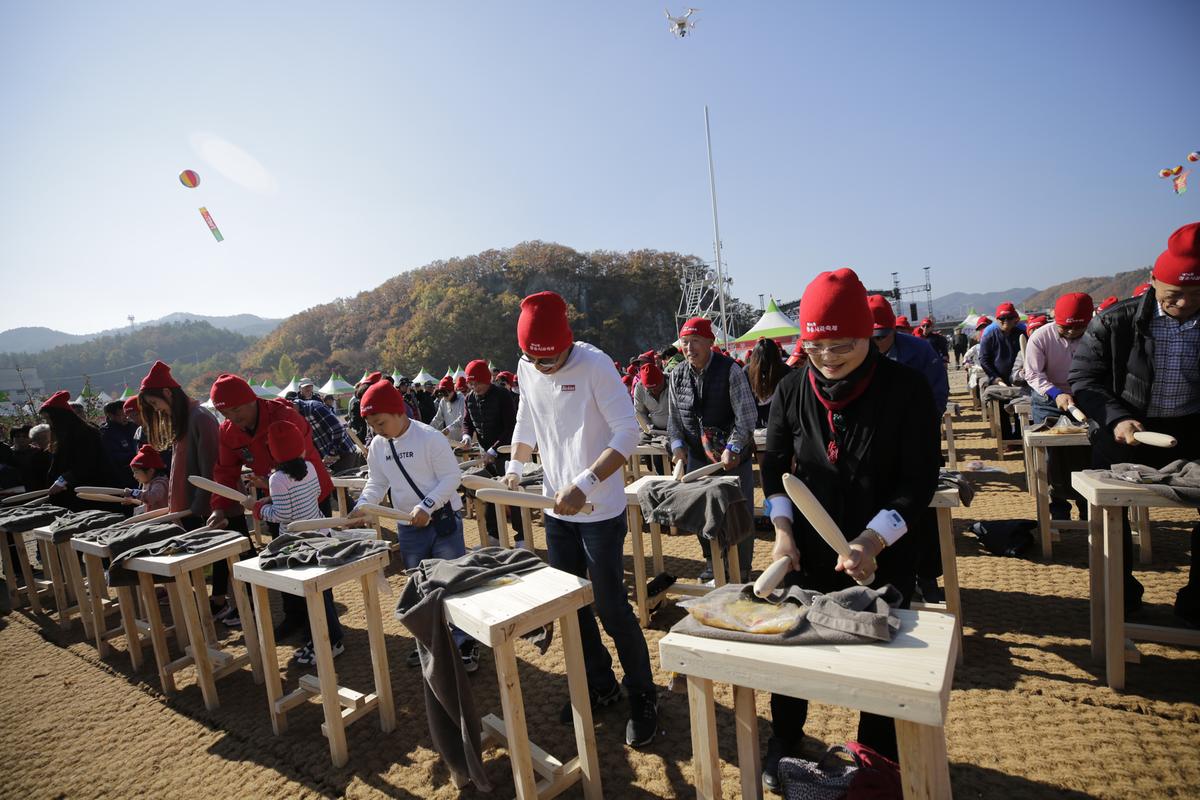 붉은 머리 수건을 쓰고 방망이로 사과가 담긴 주머니를 두드리는 사람들