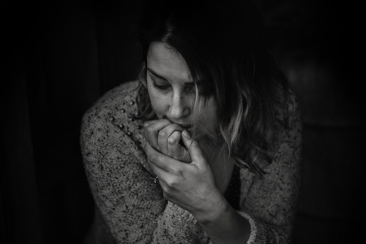 흑백 배경의 여자가 불안감에 오른손 손톱을 물어뜯고 있는 사진