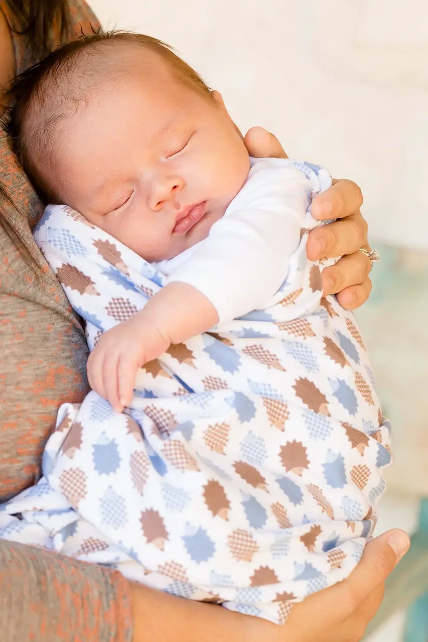 알록달록한 포데기에 감싸인채 엄마품에 안겨 잠자는 아기
