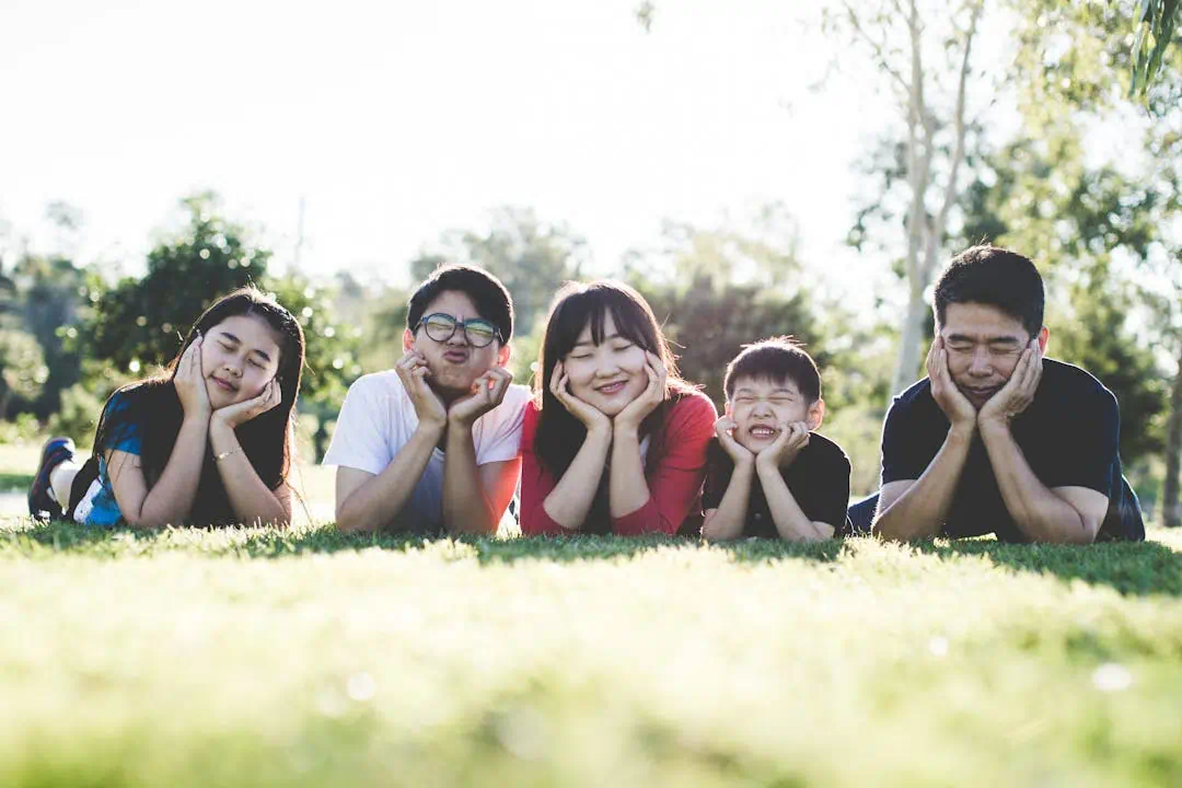 잔디밭에서 턱받침을 하고 사진을 찍는 5인가족