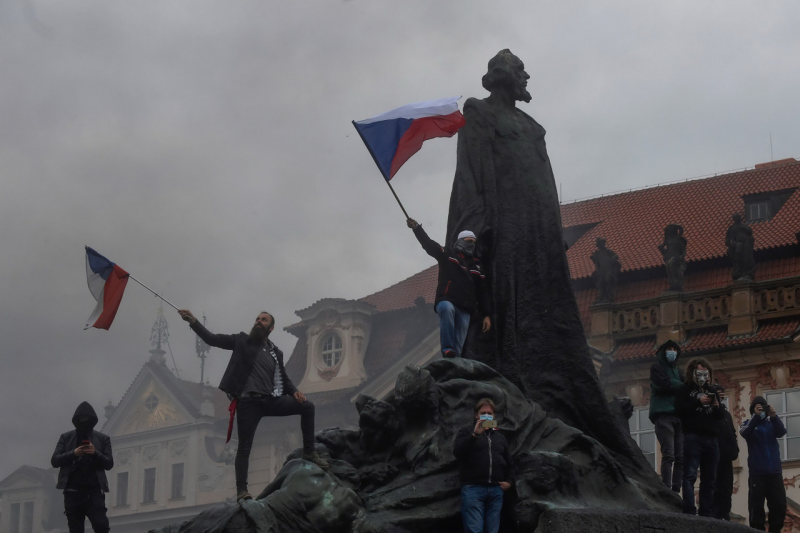 시위대가 얀 후스 동상에 올라가 국기를 흔들고 있다.