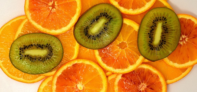 오렌지로 보이는 과일이 가로로 동그랗고 얇게 썰려 있고 그 위에 키위를 동그랗게 썰어 올려 놓아있다.