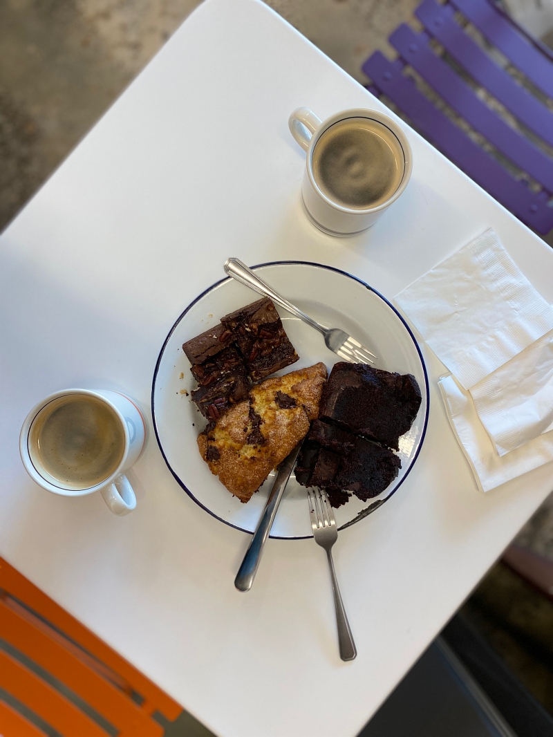 흰색 테이블위에 커피2잔과 빵이든 접시가 놓여있는 모습