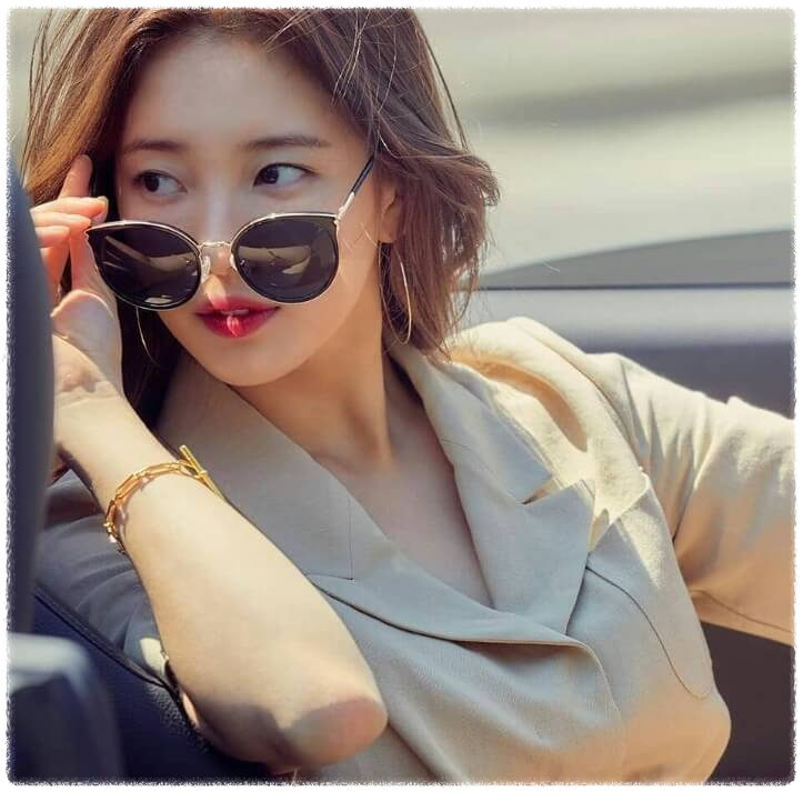 배우 수지가 차에 앉아서 쓰고 있던 선글라스를 살짝 내리고 있는 장면