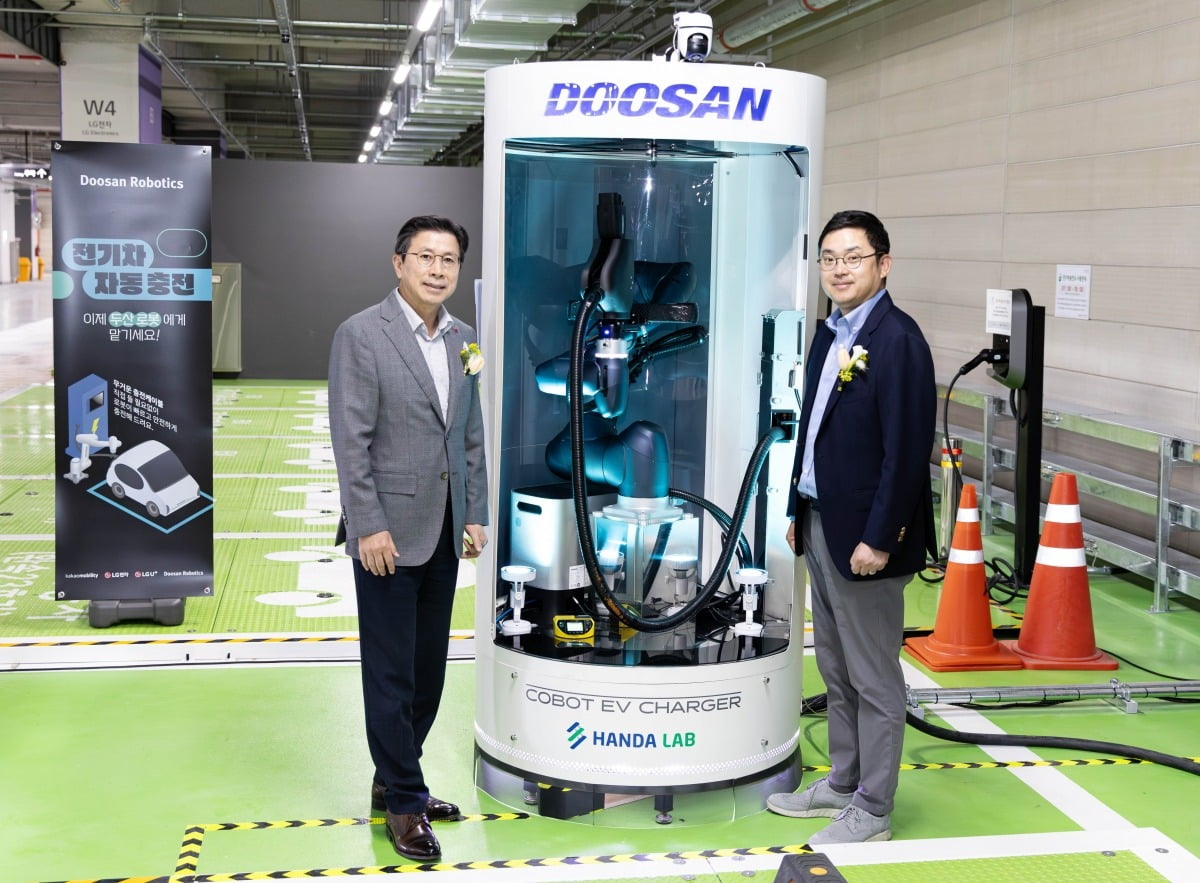 두산로보틱스 류정훈 대표(오른쪽)와 LG전자 장익환 BS사업본부장이 협동로봇을 활용한 전기차 자동 충전 솔루션 옆에서 기념사진을 촬영하고 있다.